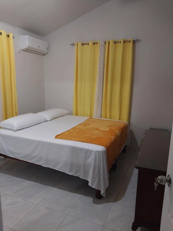 a bedroom with a bed with yellow curtains at Debs Cozy Cove in Discovery Bay