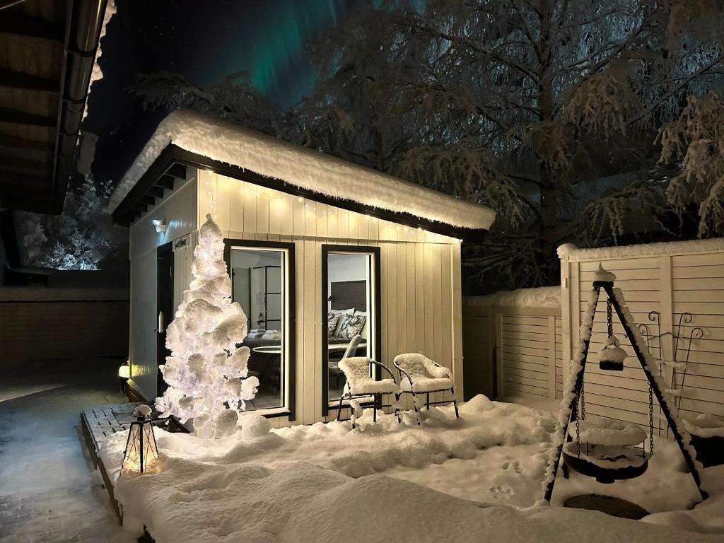 une maison recouverte de neige avec un arbre de Noël dans l'établissement Guest house - Northern tealight, à Rovaniemi