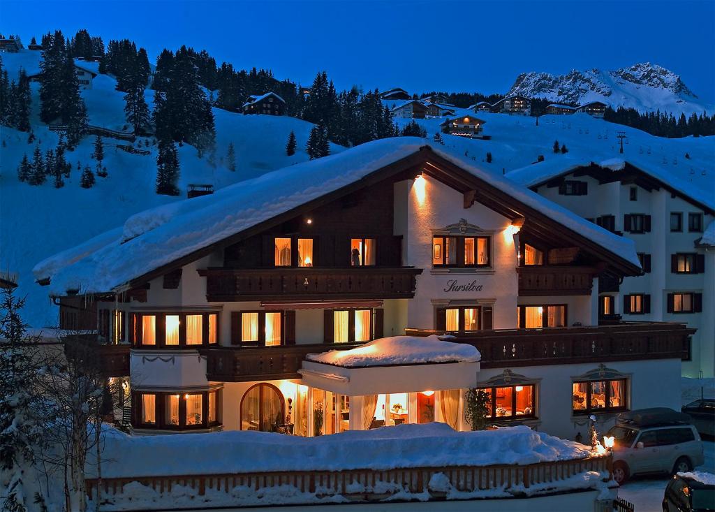 ein großes Gebäude im Schnee in der Nacht in der Unterkunft Hotel Garni Sursilva in Lech am Arlberg