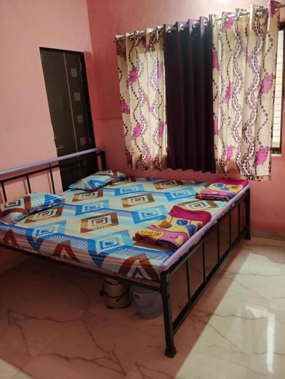 a bed with a quilt on it in a room at Laxmi Cottage in Matheran
