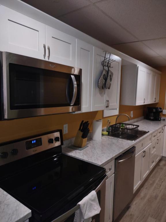 uma cozinha com armários brancos e um micro-ondas de aço inoxidável em Unique Center Of Downtown Elmira em Elmira