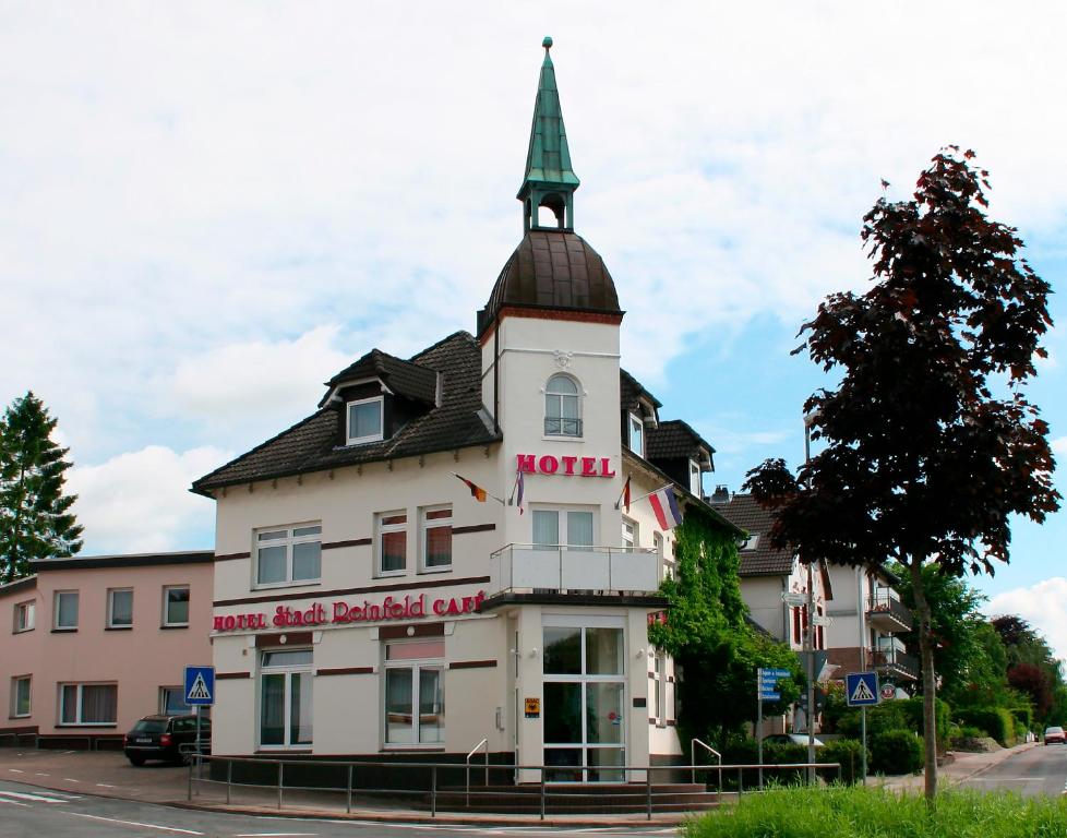 a white building with a steeple on a street at Hotel Stadt Reinfeld in Reinfeld