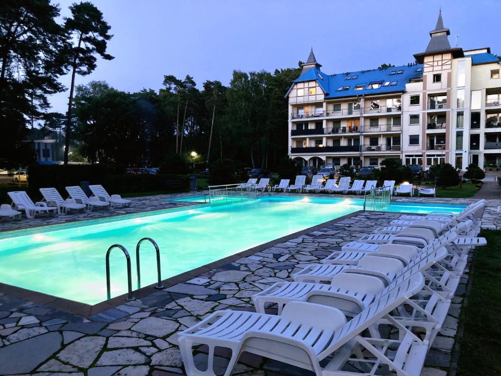 uma piscina com espreguiçadeiras brancas e um hotel em Blue Mare BB em Łukęcin