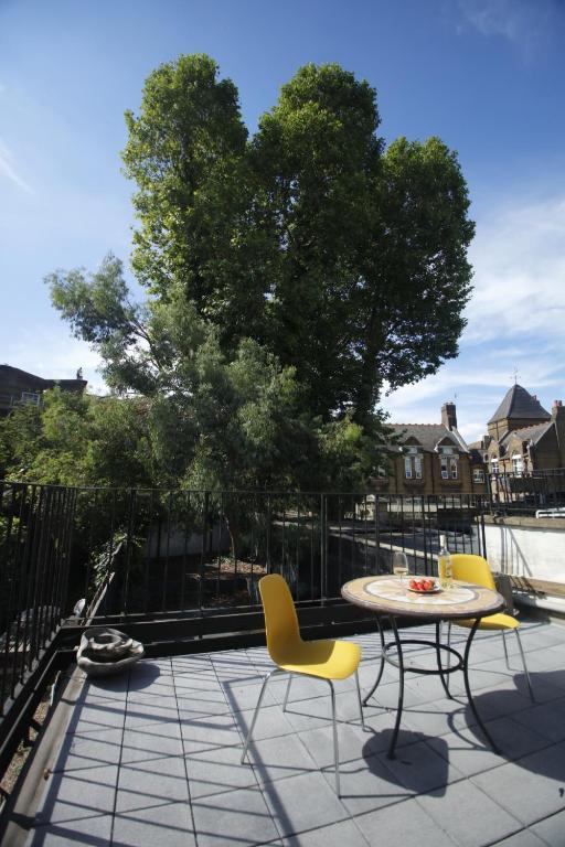 eine Terrasse mit einem Tisch, Stühlen und einem Baum in der Unterkunft COSY CAMDEN 2 BEDROOM APARTMENT WITH TERRACE in London