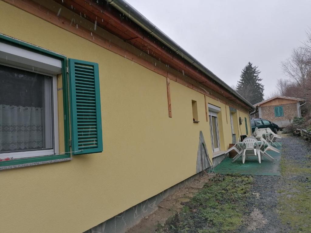a yellow house with a table and chairs on the side at Berkenyés Vendégház in Zalalövő
