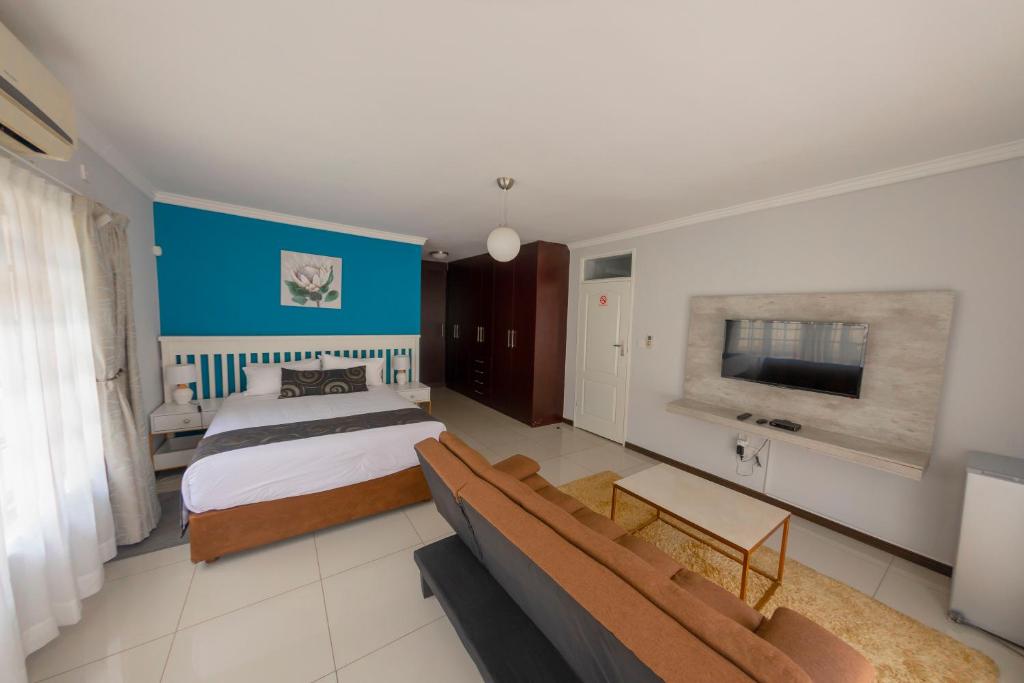 um quarto com uma cama, um sofá e uma televisão em Green Lagoon Guest House Tawana em Gaborone