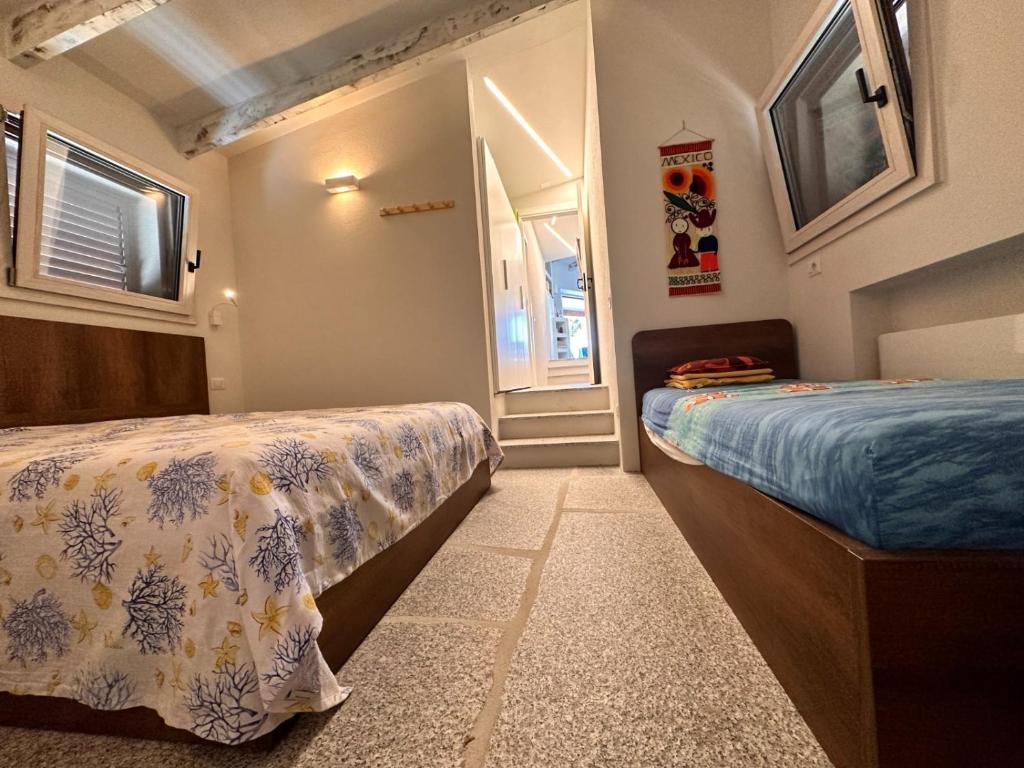 a bedroom with two beds and a window and a door at Charlie Home - Heart of Sardinia in Costa Paradiso