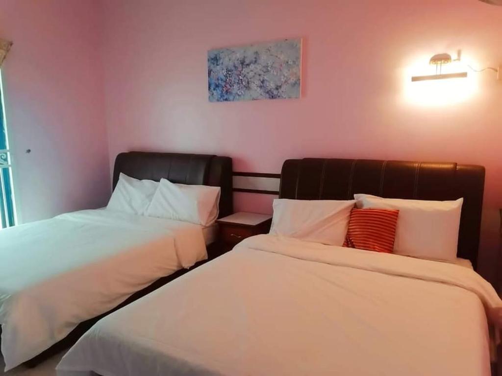 2 camas en una habitación con paredes rosas en Secret Garden, en Kampong Alor Gajah