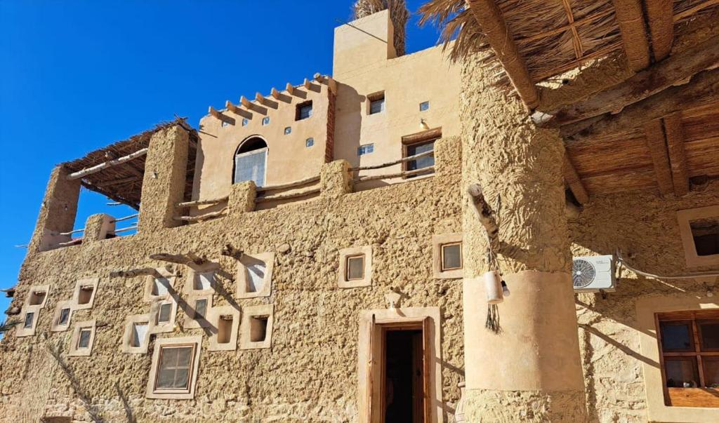 un edificio de piedra con una puerta delante en مراقي سيوة Maraqi Siwa, en Siwa