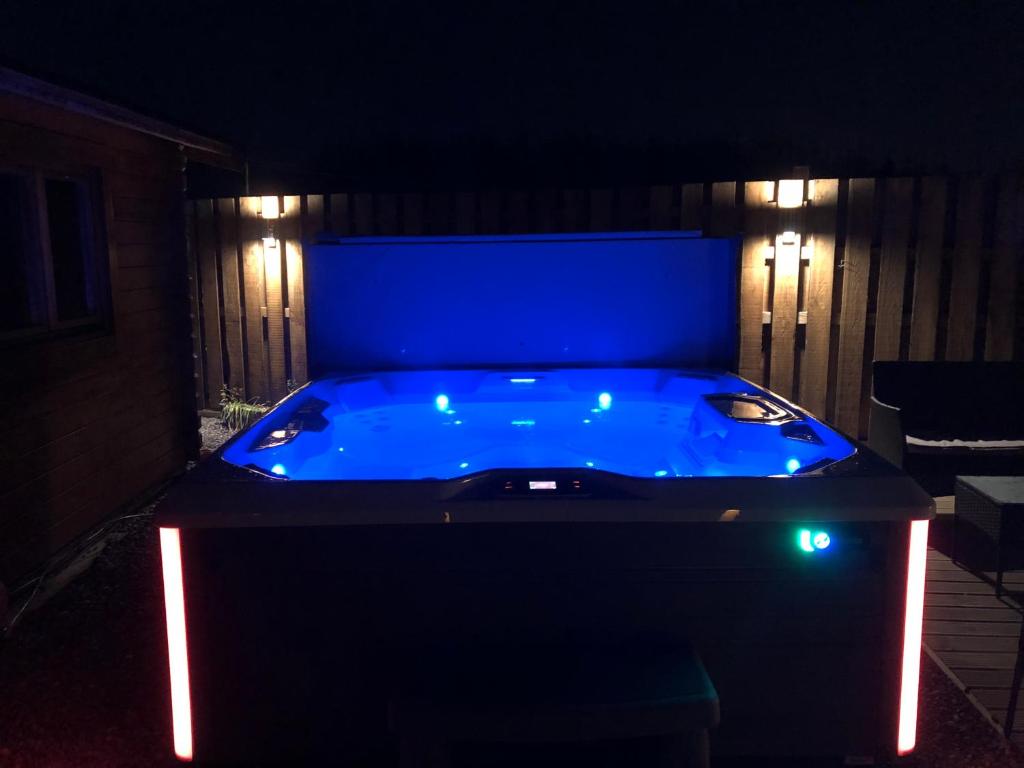 a blue hot tub in a backyard at night at Lochinvar - Highland Log Cabin with Private Hot Tub in Airdrie
