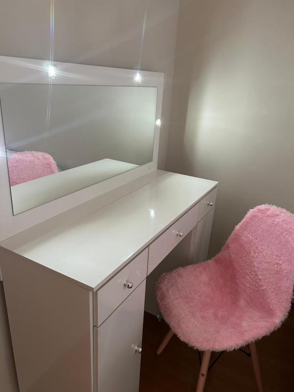 uma secretária branca com um espelho e uma cadeira rosa em Apartamento inteiro acomoda 5 pessoas em Uberlândia