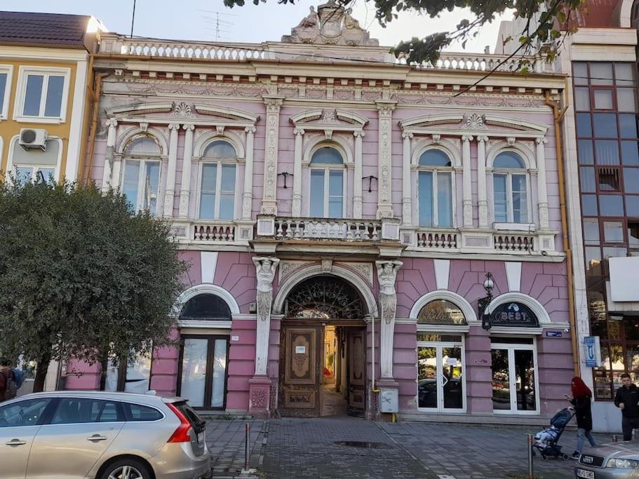 a pink building with a car parked in front of it at Emese Central Vintage Apartment in Târgu-Mureş