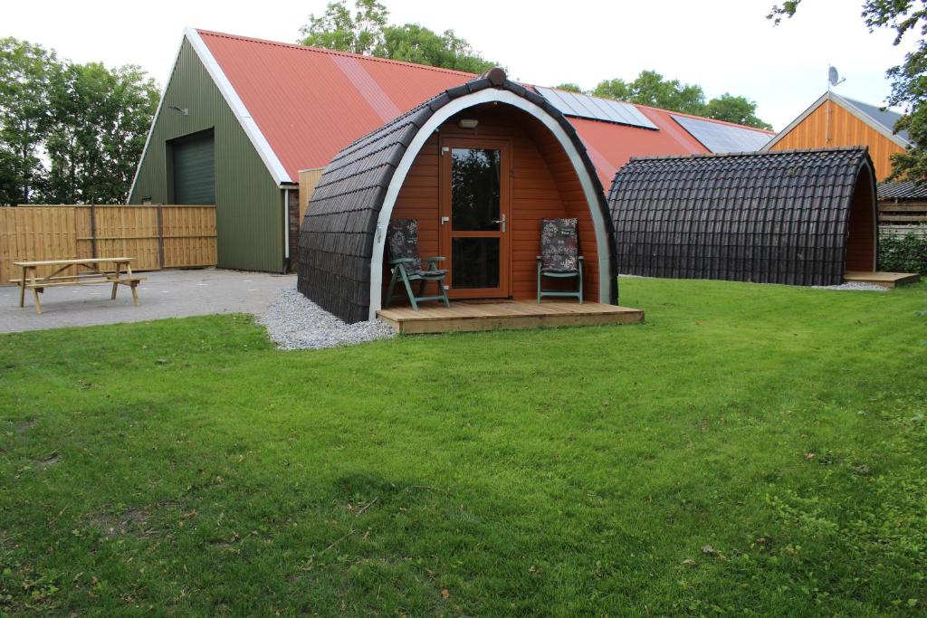 Cabaña pequeña con techo rojo en un patio en Camping pod: Lyts Dekema 2 en Baard