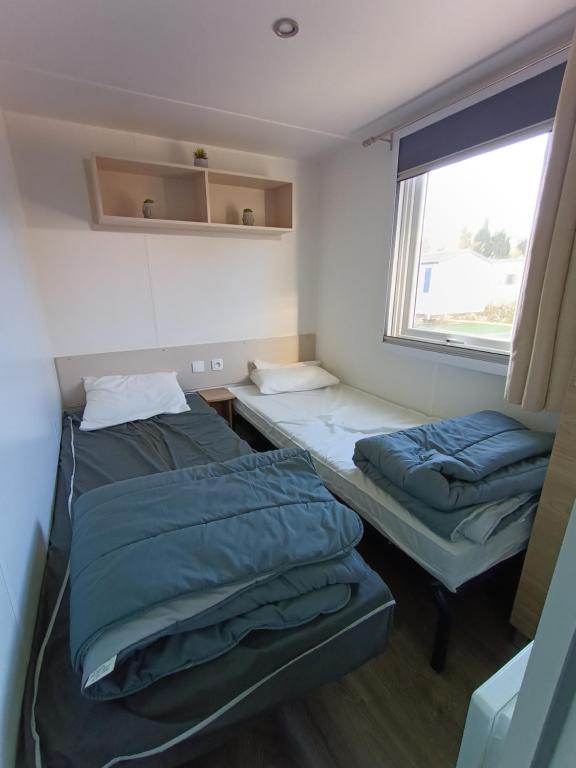 two beds in a room with a window at Camping SIBLU les sables du midi à Valras plage in Valras-Plage