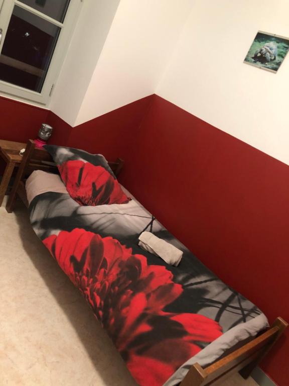 Ce lit se trouve dans une chambre dotée d'un mur rouge. dans l'établissement rest'hôtel l'ardoise Chambre N 4, à Augé