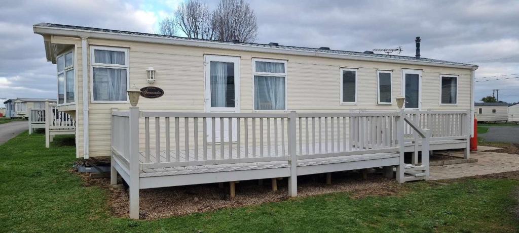 a white house with a porch and a fence at Dog Friendly Caravan Heacham Norfolk Holiday in Heacham