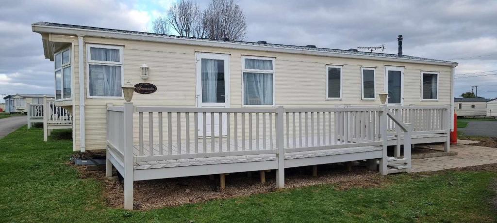 ein weißes Haus mit einer Veranda und einem Zaun in der Unterkunft Dog Friendly Caravan Heacham Norfolk Holiday in Heacham