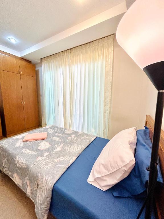 Un dormitorio con una cama azul con una lámpara y una ventana en S304 Good Apartment Chalong Na-Kok Mauy-Thai, en Ban Na Kok