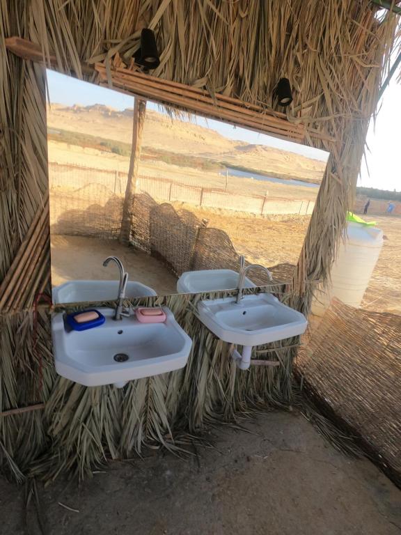 Dār as Salām的住宿－flamingo camp，一间位于稻草小屋内且带两个水槽的浴室