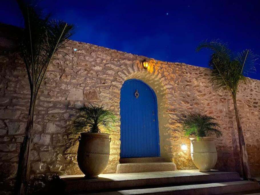 un edificio con una puerta azul y dos palmeras en Jolie propriété de campagne calme et spacieuse 