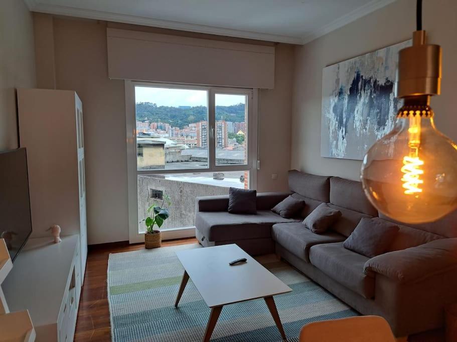 een woonkamer met een bank en een groot raam bij 2 habitaciones en piso Bilbao in Bilbao