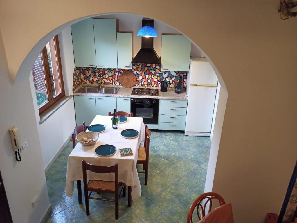 a kitchen with a table and chairs and a kitchen with white cabinets at Casa blu Arbatax con giardino e terrazza in Tortolì