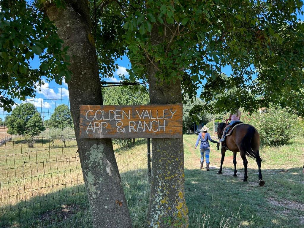 Martinski的住宿－Golden Valley apartment & ranch，一位妇女沿着标志旁的小径走着马