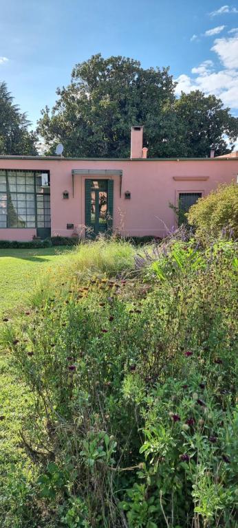 ein rosa Haus auf einem Grasfeld in der Unterkunft La Centenaria, casa de campo in Bragado