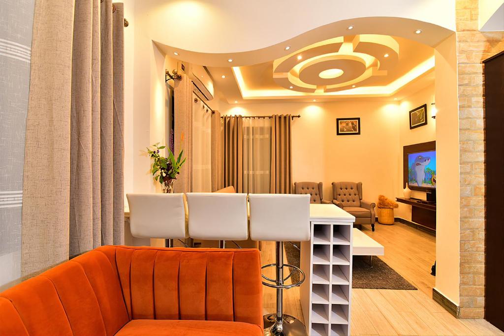 ENTEBBE STAY Apart-Hotel في عنتيبي: غرفة معيشة مع أريكة برتقالية وطاولة