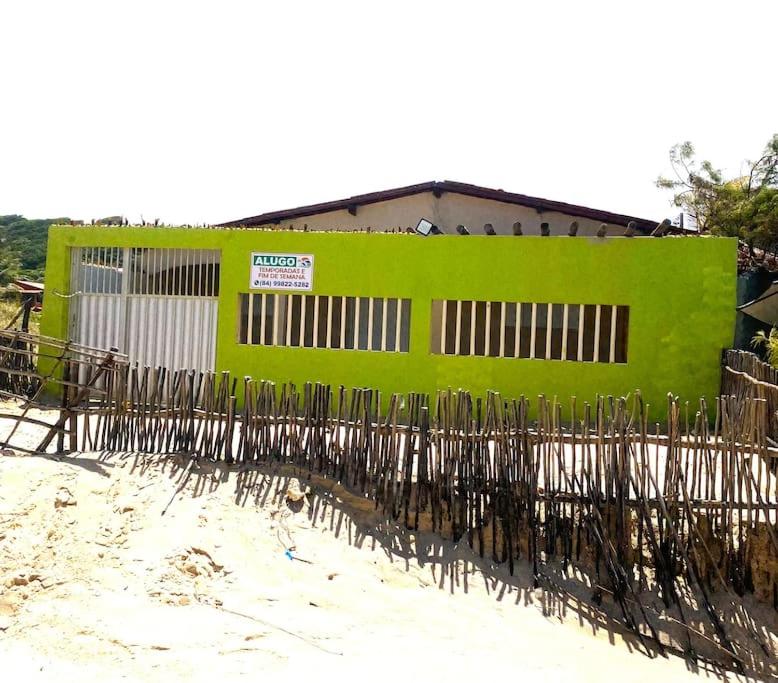a fence in front of a green building at Paz, arte, beleza e natureza na praia de Sagi in Baía Formosa