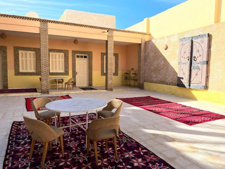 eine Terrasse mit einem Tisch und Stühlen auf einem Teppich in der Unterkunft Dar Medina Tozeur in Tozeur