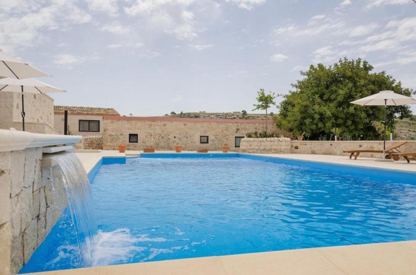 uma grande piscina azul com um guarda-sol em Villa Dolce Valle em Ragusa