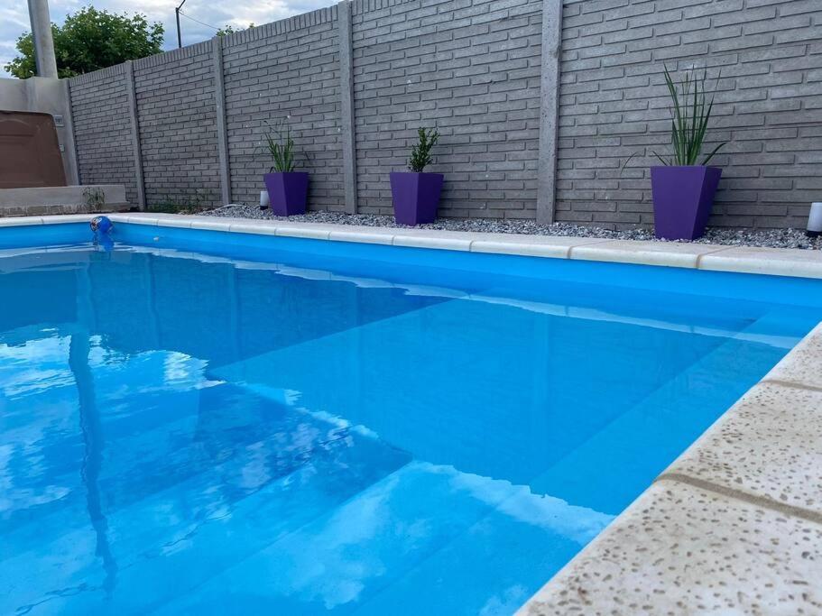 una piscina blu con piante in vaso accanto a un muro di mattoni di Casa quinta , ideal descanso 