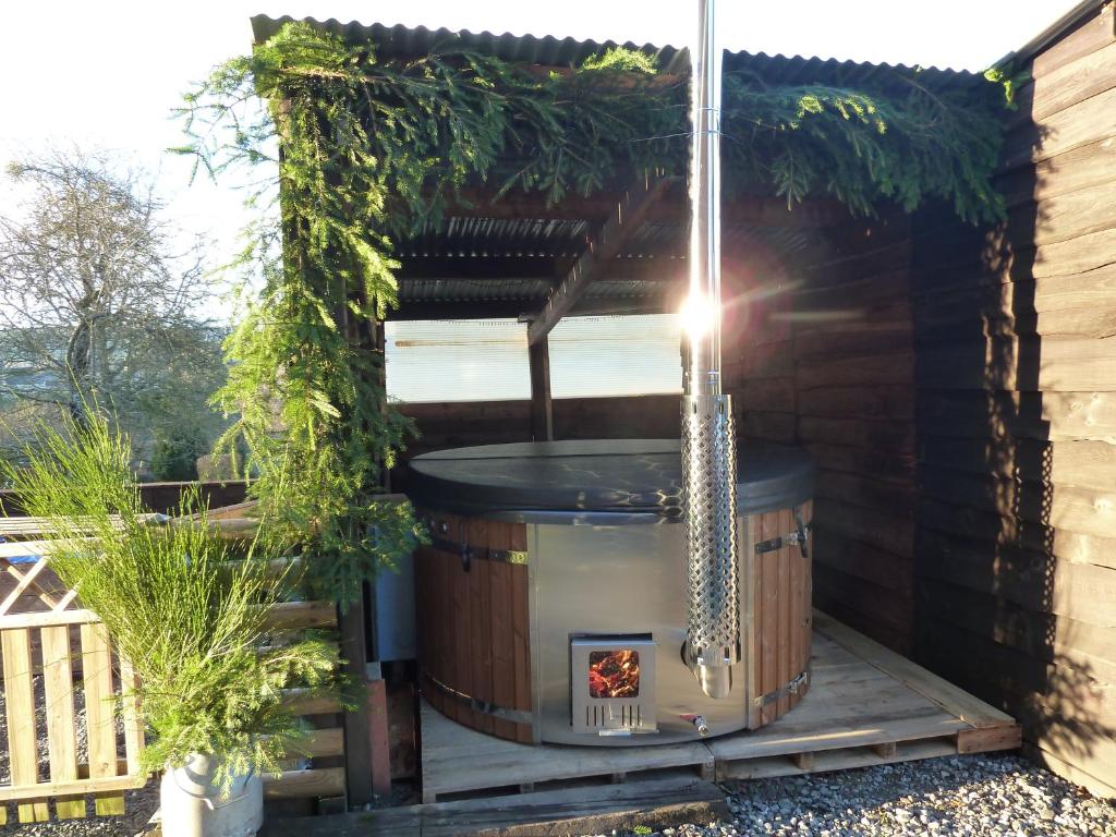 una bañera de hidromasaje en un patio trasero con pérgola en 'Chez Lulu' - Gîte cocon avec bain nordique Ardenne, en Au delà de lʼEau
