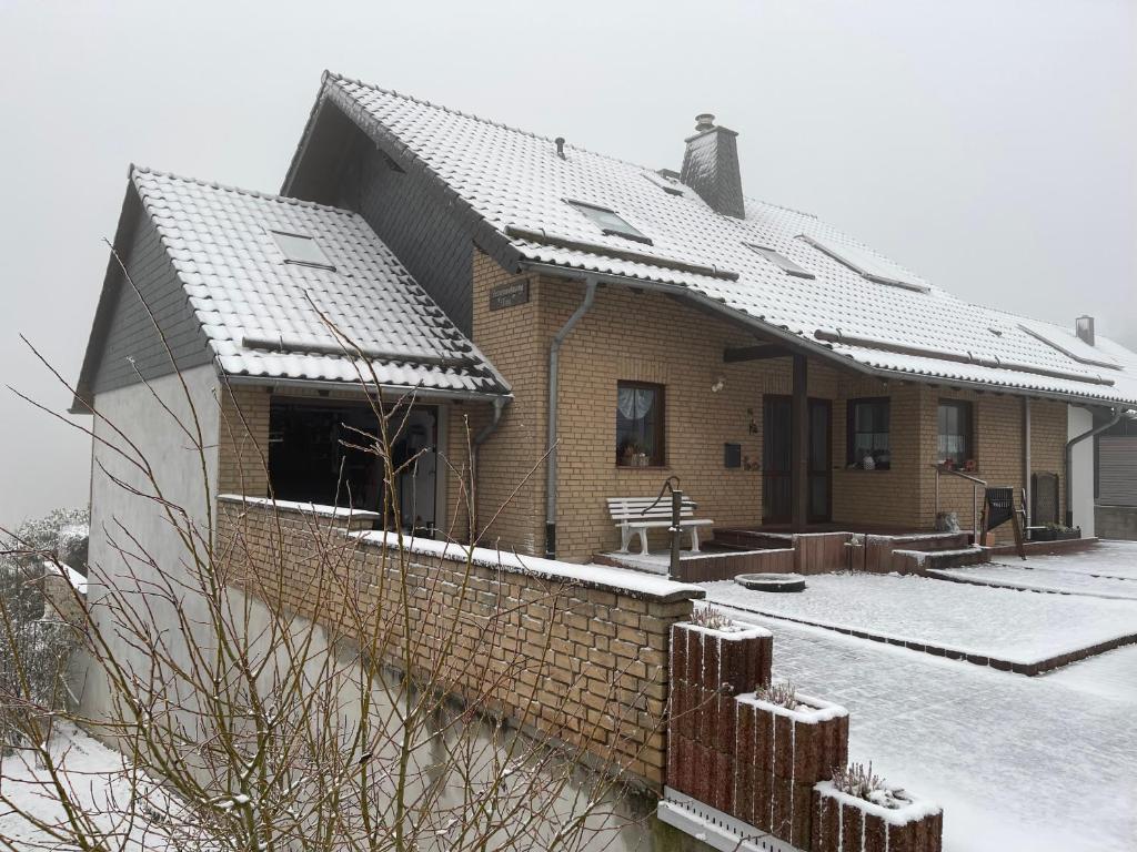 Ferienwohnung Tina في Nettersheim: منزل من الطوب والثلج على السطح