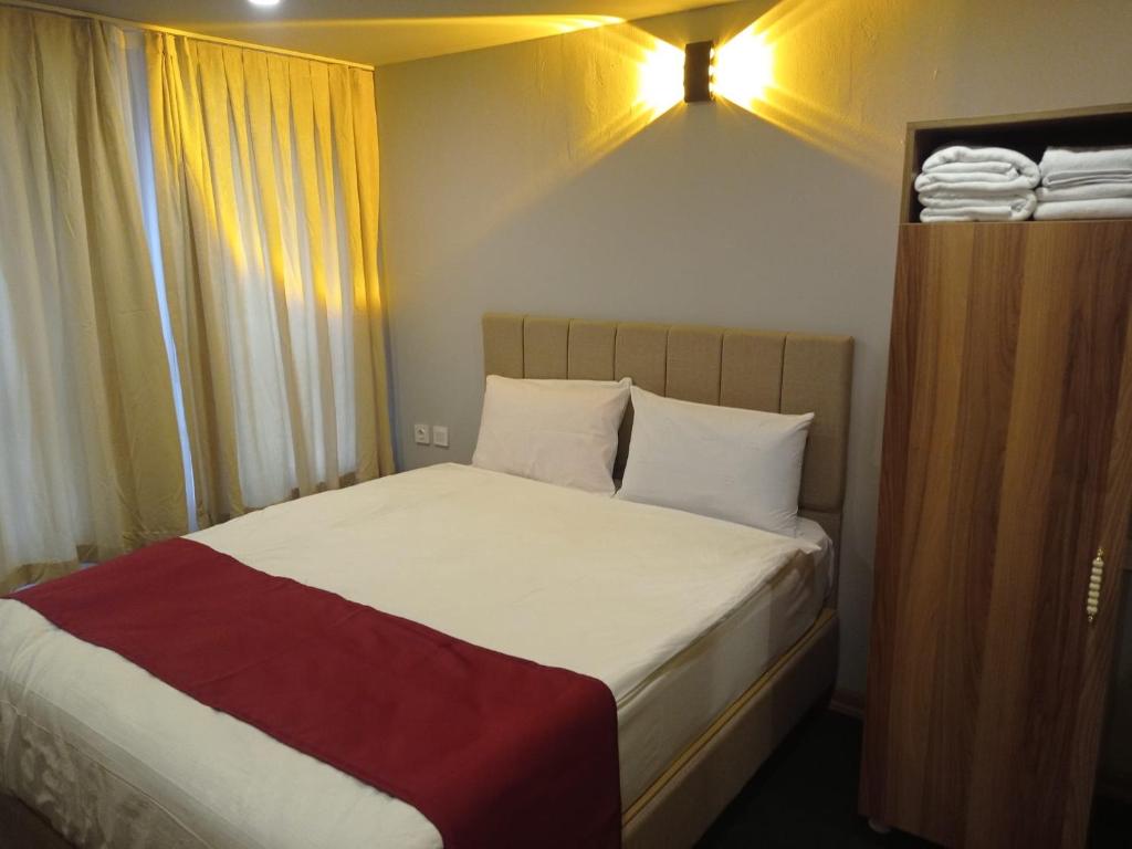 a small bedroom with a bed with white sheets and red blanket at Grand Marrakech Hotel in Yıldırım