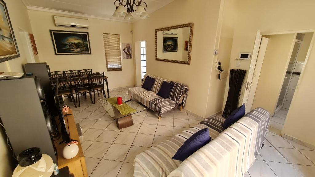 a living room with a couch and a dining room at Garden Oasis Cottage in Windhoek
