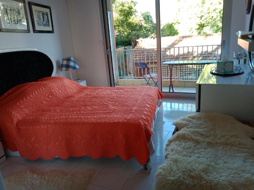 Schlafzimmer mit einem roten Bett und einem Balkon in der Unterkunft APPARTEMENT AU CALME in Menton