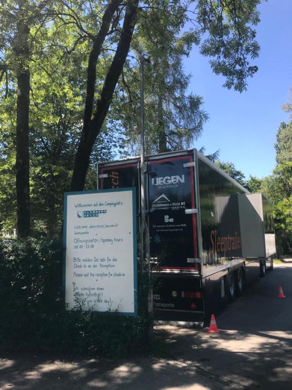 un grand bus est garé à côté d'un panneau. dans l'établissement Sleeptrailer, à Zurich