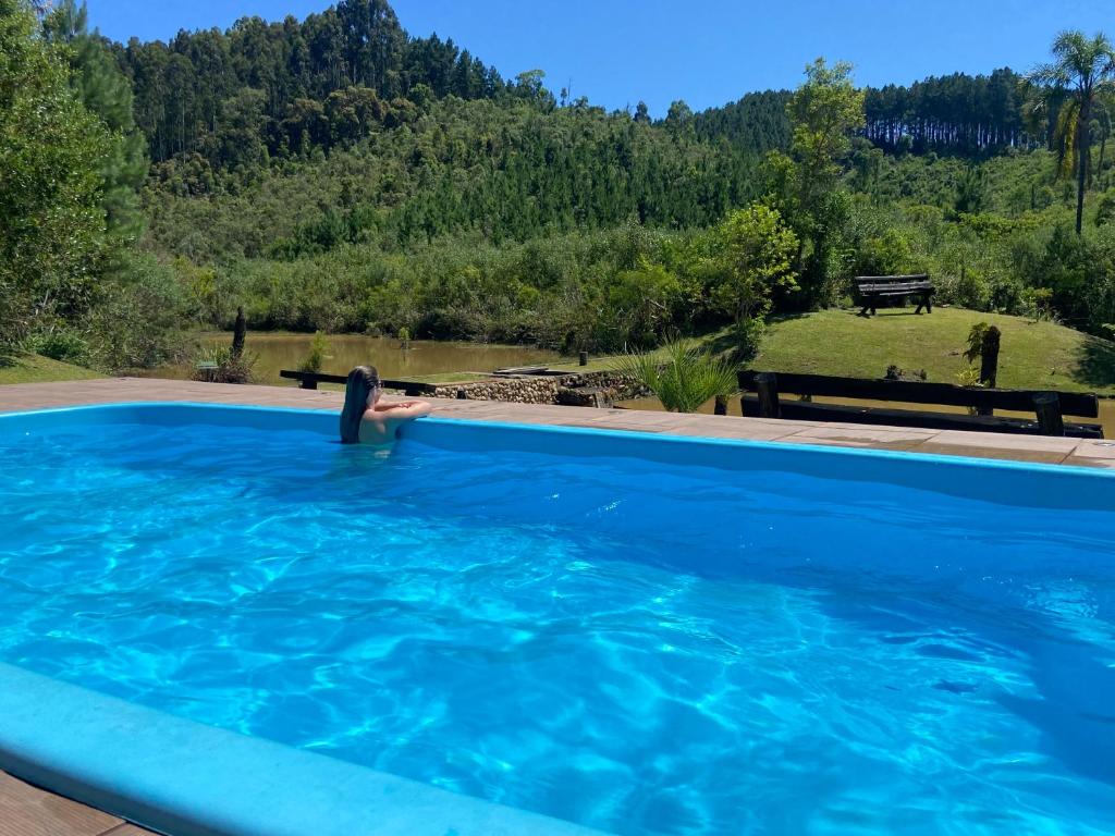 een persoon in een zwembad met een paddle bij Recanto da Felicidade para 13 pessoas in Annitapolis