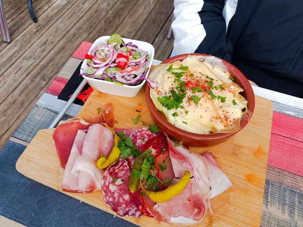 uma tábua de cortar com carne e legumes e uma salada em Les myrtilles La Pierre Saint Martin em Arette