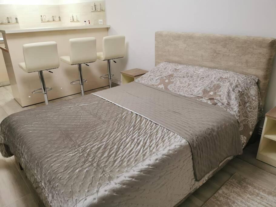 ein Schlafzimmer mit einem großen Bett mit 2 Stühlen in der Unterkunft RG Garsoniera Central in Piatra Neamţ
