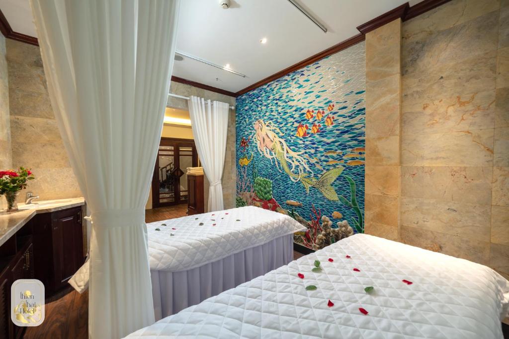 a bedroom with two beds and a mural at Thien Thai Hotel & Spa in Hanoi