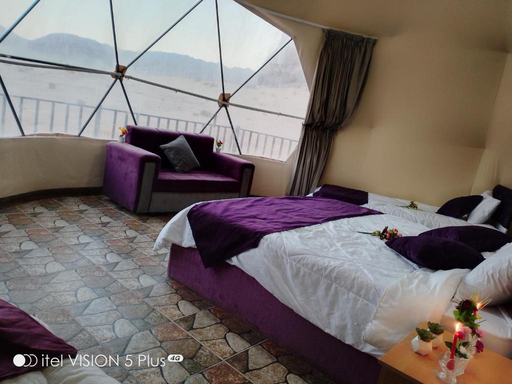 a bedroom with a purple bed and a window at wadi rum caeser camp in Wadi Rum