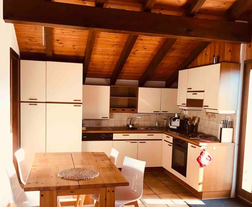 una cucina con tavolo in legno ed elettrodomestici bianchi di Chez Marilyne a Savièse