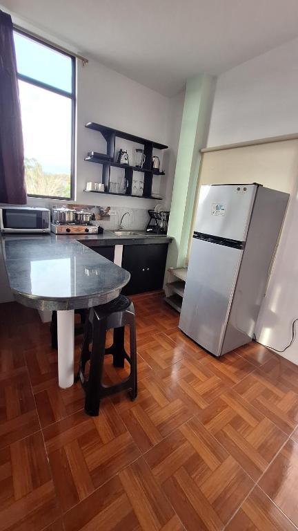 Galápagos Brunette Suites I في بويرتو أيورا: مطبخ مع طاولة وثلاجة