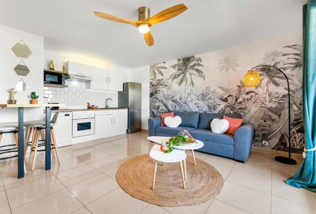 sala de estar con sofá azul y cocina en La Créola New! Grand Case - vue mer - appart 4p - King size, en Grand Case
