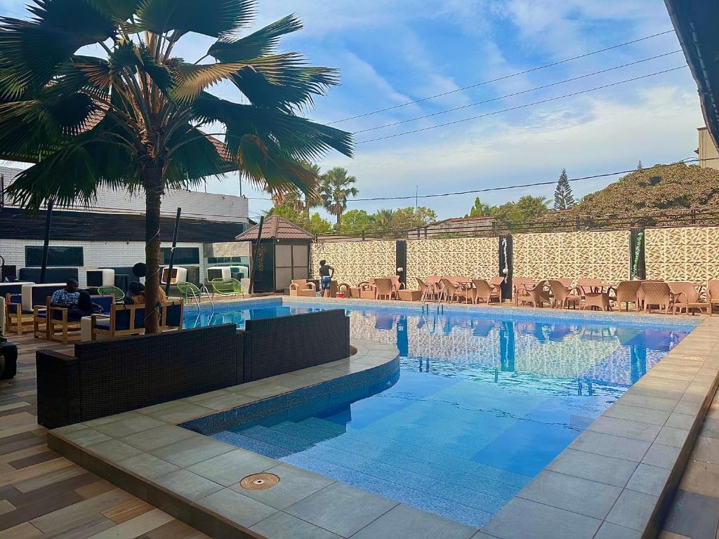 una piscina con una palmera al lado de un edificio en Apartments Plaza Hotel en Kololi
