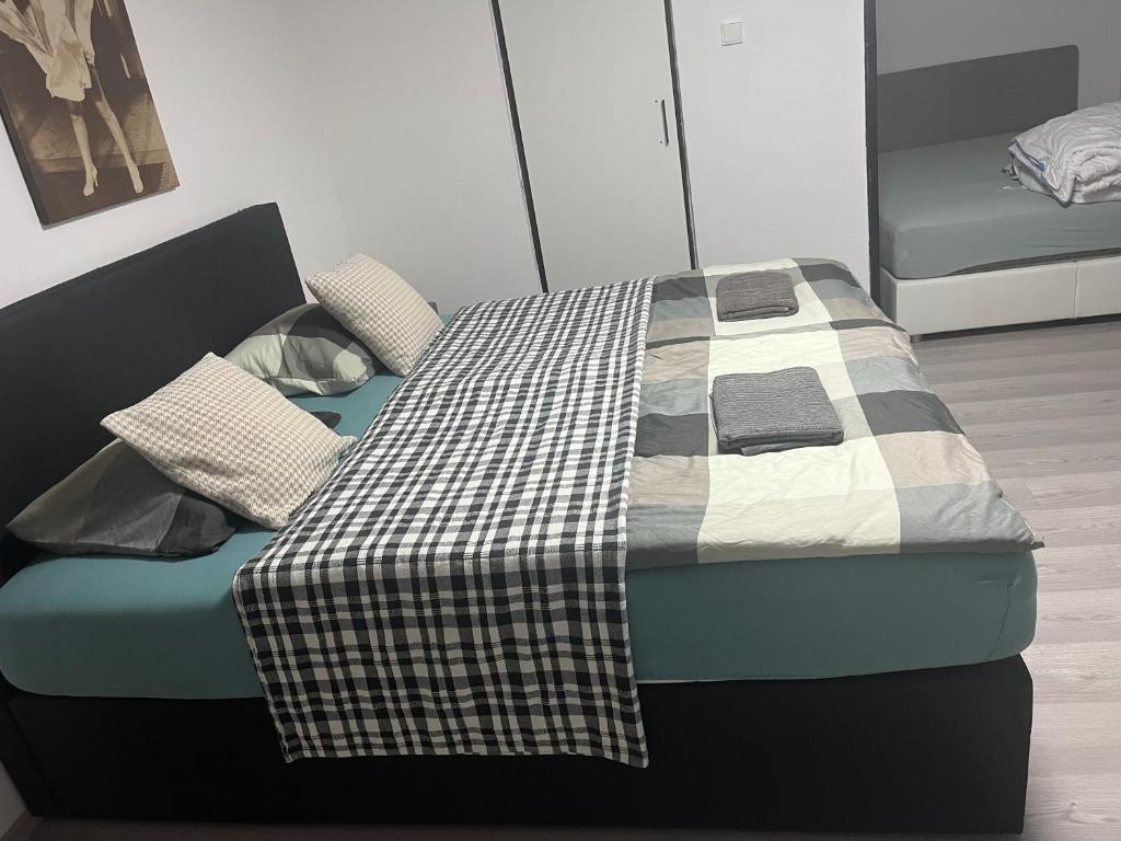 a bed with a checkered blanket and pillows on it at Apartmánek Patricie room with kitchenette suitable for 2 adults and 2 children in Mikulov