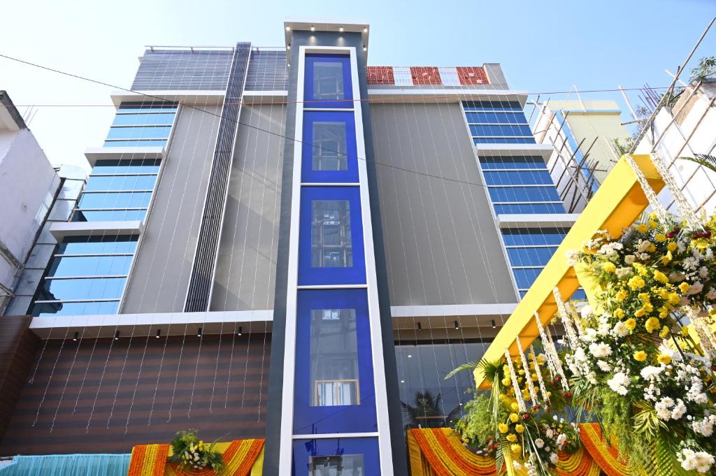 a tall building with blue trim and flowers in front at HOTEL PRAJYOT in Pūrnia